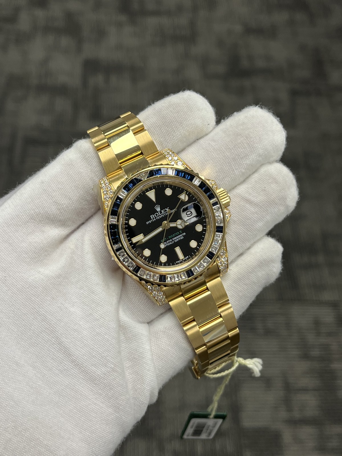 Gem-set gold Rolex GMT-Master II held in a white glove