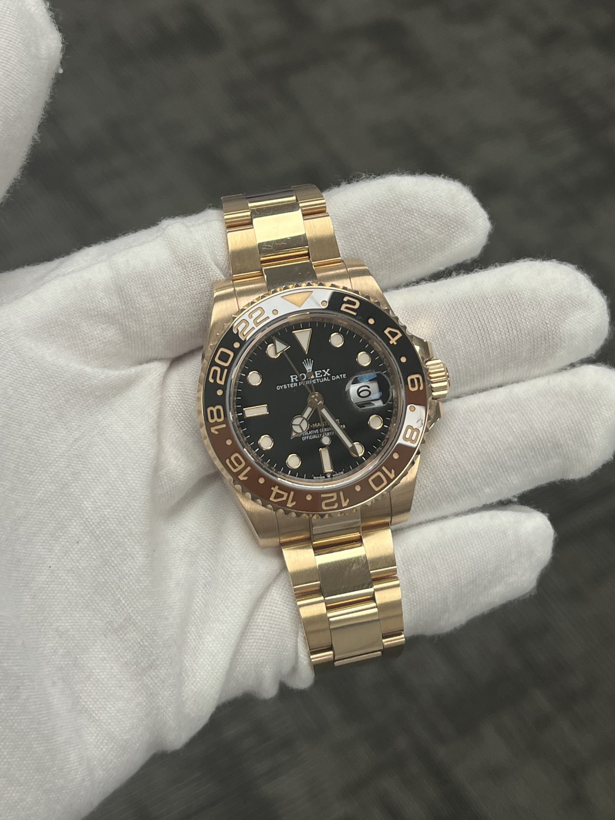 Gold Rolex GMT-Master II held in a white glove