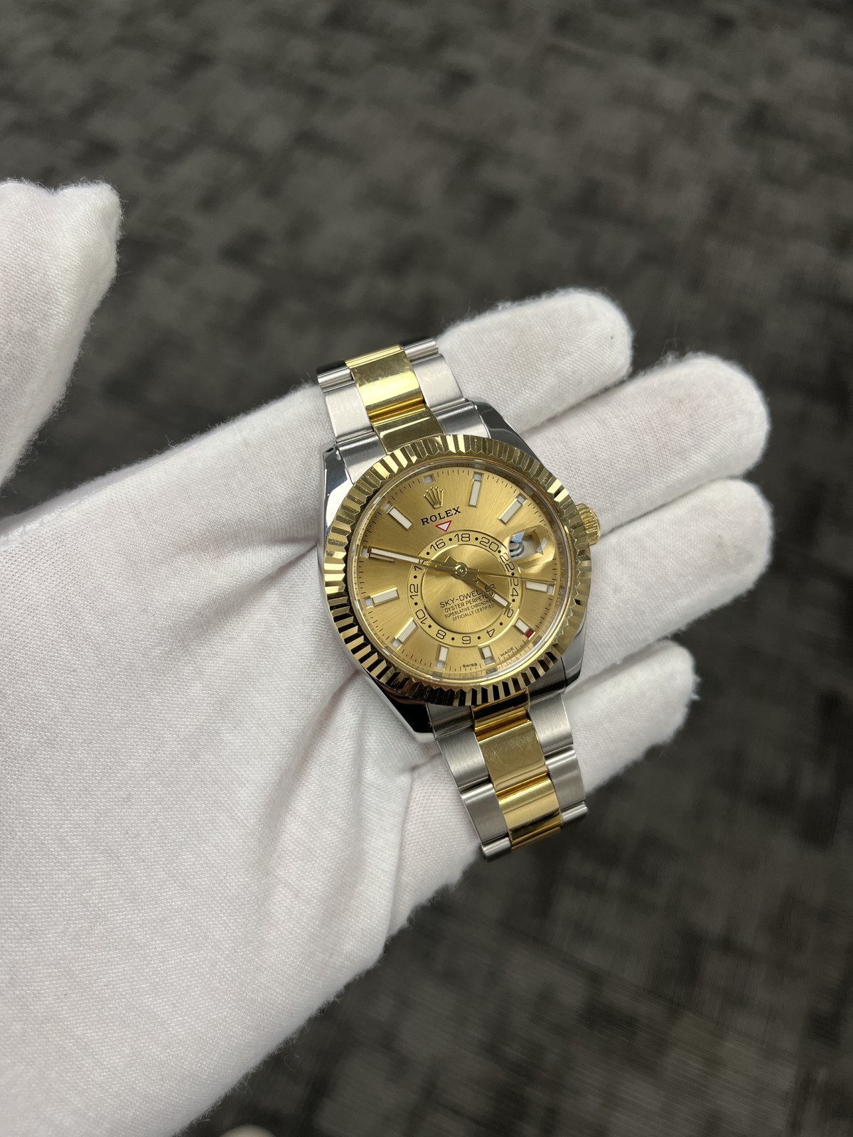 Two-tone Rolex Sky-Dweller held in a white glove